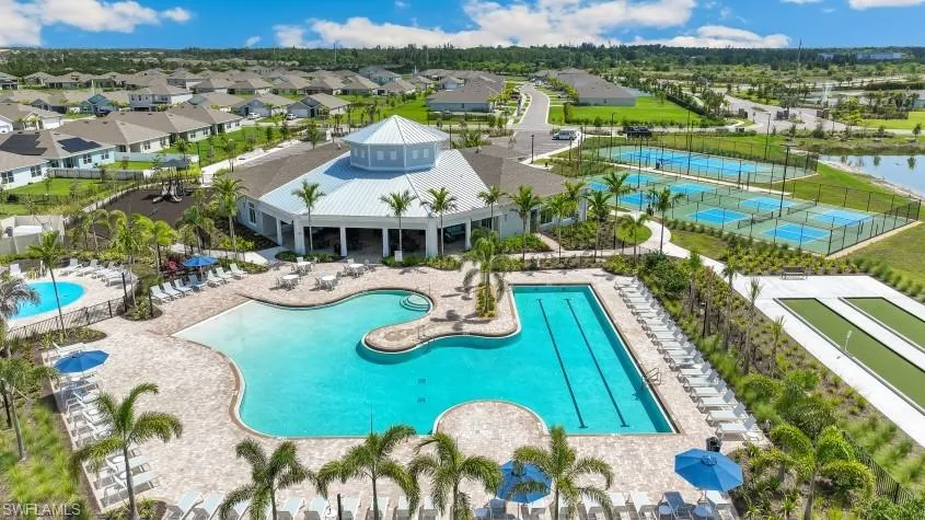 Community club house with two swimming pools, a wading pool, lounge chairs, tennis courts, and bocce ball courts