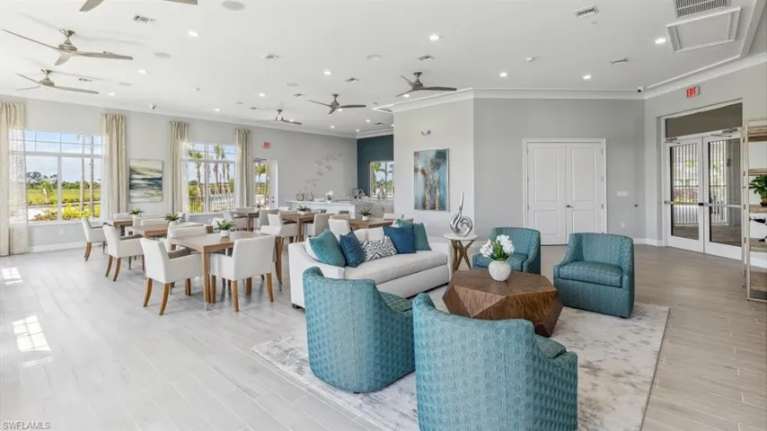 Expansive common room with light-colored flooring, large windows, and ceiling fans