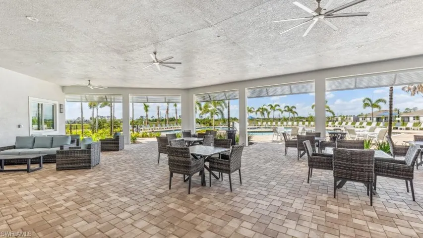 Outdoor covered patio area featuring ceiling fans and a patterned paver floor