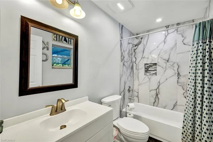 Bathroom featuring vanity and shower / bathtub combination with curtain