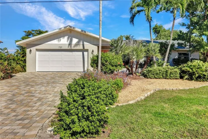 Ranch-style home with decorative driveway, a garage, a front yard, and stucco siding