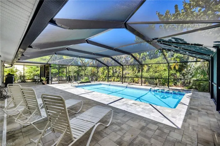 Outdoor pool featuring a patio, a sunroom, and glass enclosure