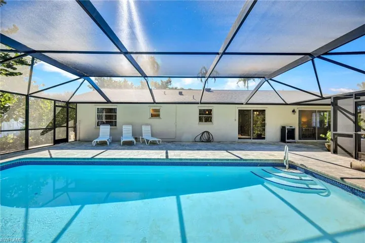 Outdoor pool with a sunroom, glass enclosure, and a patio