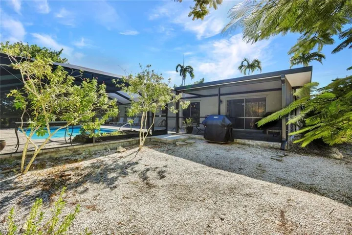 Rear view of property featuring a sunroom, a lanai, a patio area, and an outdoor pool
