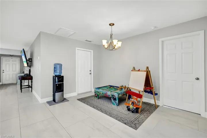 Recreation room with a chandelier and light tile patterned floors