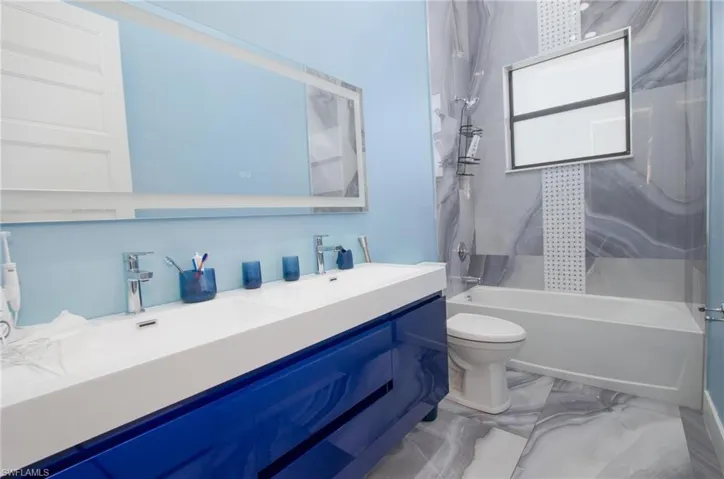 Full bathroom with vanity, tiled shower / bath combo, and toilet