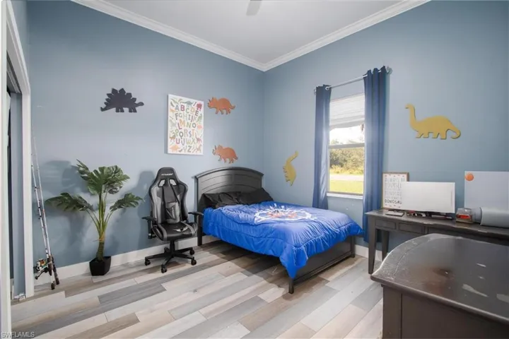 Bedroom featuring light hardwood / wood-style floors, ceiling fan, and crown molding