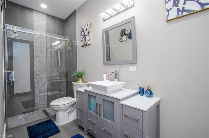 Bathroom featuring tile patterned flooring, vanity, toilet, and walk in shower
