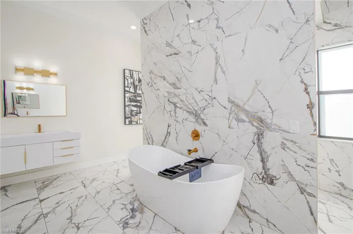 Bathroom with a tub to relax in, plenty of natural light, vanity, and ornamental molding