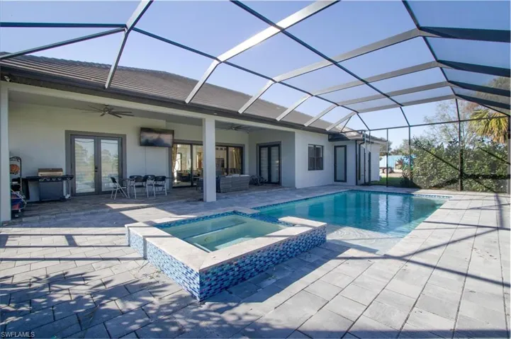 View of pool with french doors, ceiling fan, a lanai, an in ground hot tub, and a patio area