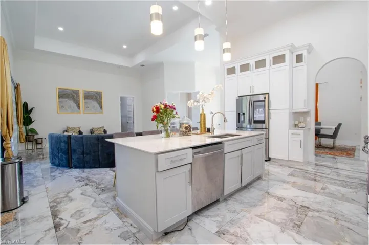 Kitchen with white cabinetry, sink, pendant lighting, a center island with sink, and appliances with stainless steel finishes
