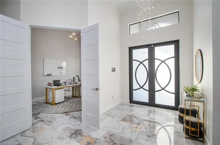 Foyer with french doors, ornamental molding, a high ceiling, and an inviting chandelier
