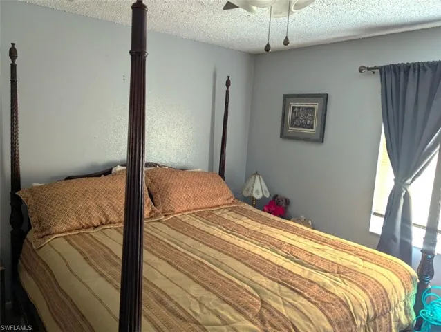 Bedroom with ceiling fan and a textured ceiling