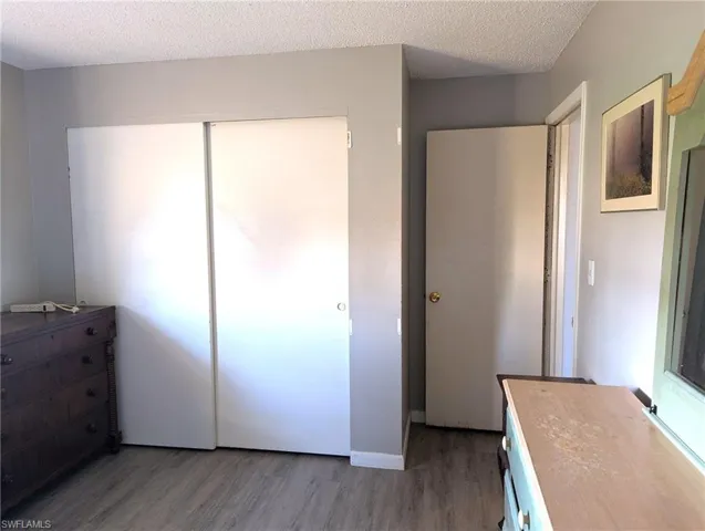 Unfurnished bedroom featuring a closet, dark hardwood / wood-style flooring, and a textured ceiling