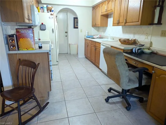 Kitchen with white dishwasher, light tile patterned floors, tasteful backsplash, and sink