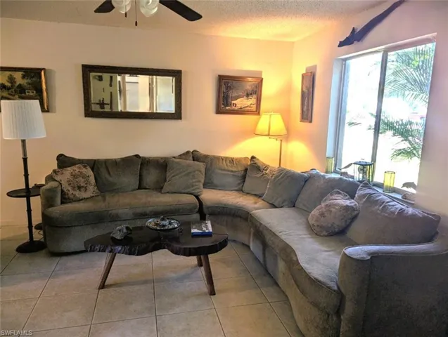 Living room featuring light tile patterned floors, a textured ceiling, and ceiling fan