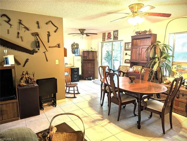 Dining area featuring ceiling fan, light tile patterned floors, and a textured ceiling