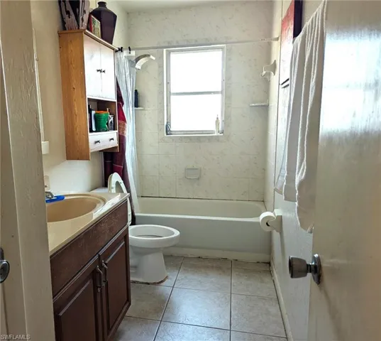 Full bathroom with shower / bath combo with shower curtain, tile patterned floors, toilet, and vanity