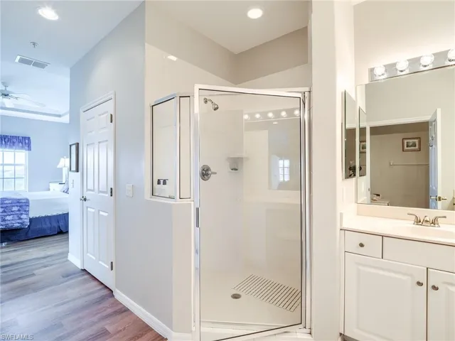 Ensuite bathroom featuring a stall shower, vanity, light wood-style floors, and recessed lighting