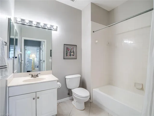 Bathroom featuring shower / tub combo with curtain, light tile patterned floors, and vanity