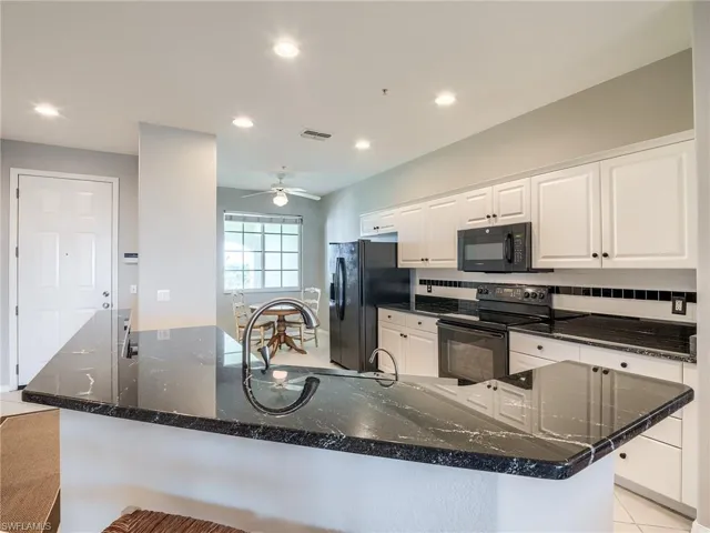 Kitchen featuring black appliances, white cabinets, recessed lighting, dark stone countertops, and decorative backsplash
