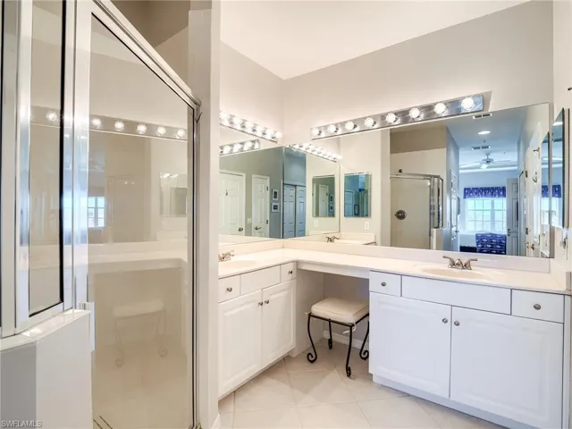 Full bath featuring a stall shower, light tile patterned floors, ensuite bathroom, and double vanity
