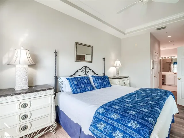 Bedroom featuring ensuite bath, ceiling fan, and dark wood-style flooring