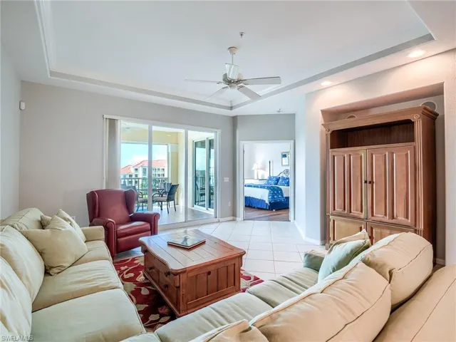 Living area featuring a raised ceiling, tile patterned floors, a ceiling fan, and recessed lighting