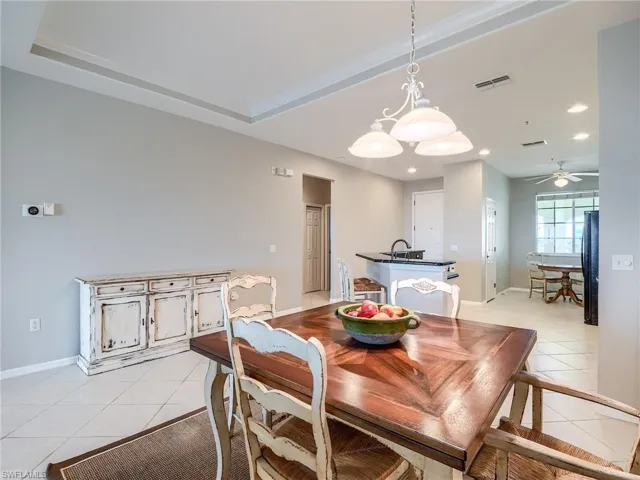Dining space with light tile patterned floors, ceiling fan, recessed lighting, and a tray ceiling
