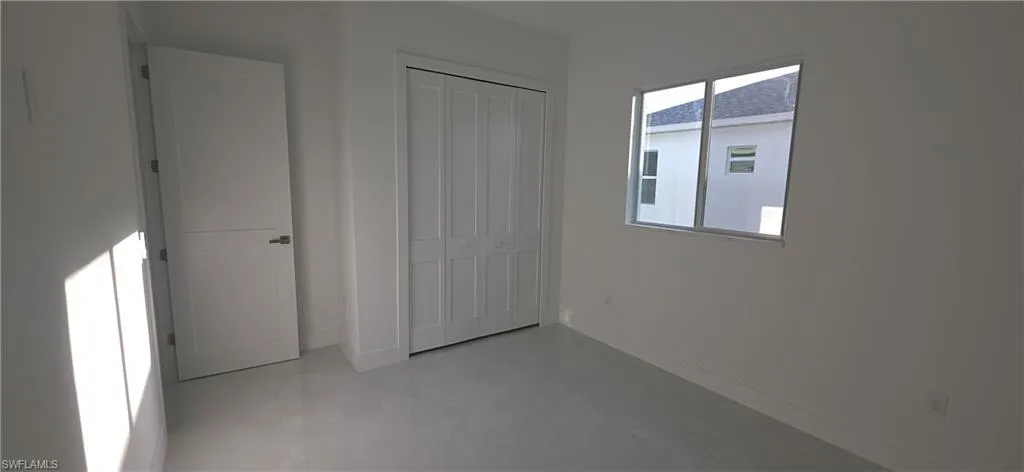 Bright interior room featuring light-toned flooring, white walls, and a modern bi-fold closet door