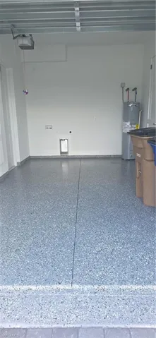 Spacious garage featuring a durable flake epoxy flooring, white painted walls, and an automatic garage door opener
