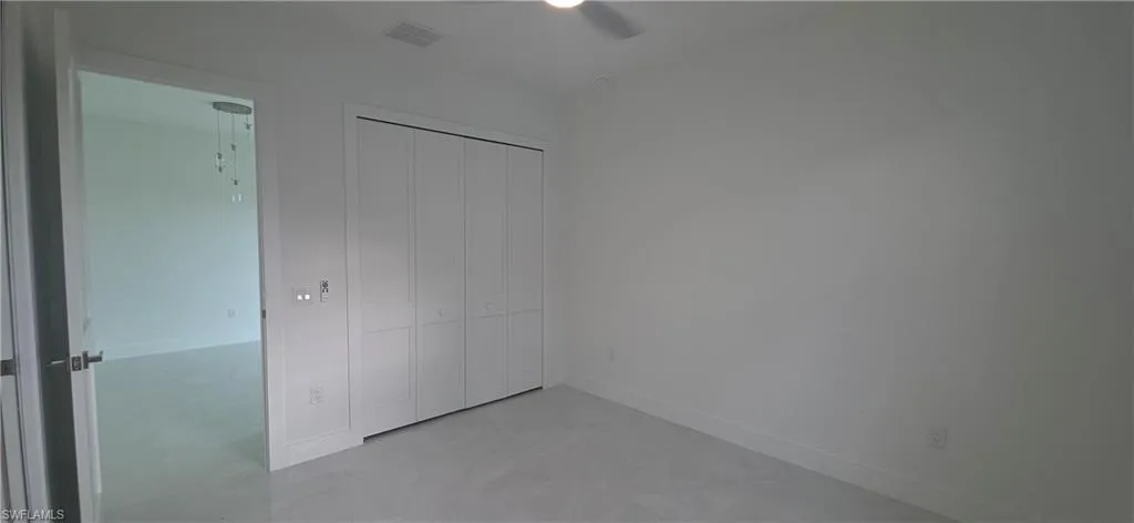 Bright room featuring a ceiling fan, light-colored floor tile, and a double bi-fold closet