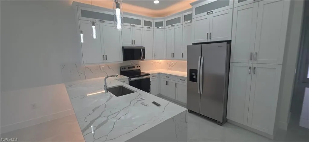 Kitchen featuring an expansive island with a waterfall-edge countertop, an undermount sink, and a high-arc faucet