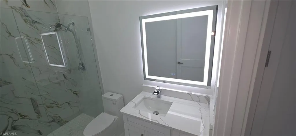 Bathroom featuring a modern vanity with integrated sink, chrome faucet, and stone countertop