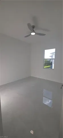 Spacious room featuring light-toned flooring, white walls, and a modern ceiling fan with integrated lighting