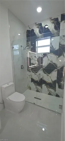 Bathroom featuring a glass-enclosed shower with contrasting wall tiling, a linear drain, and a rain shower head