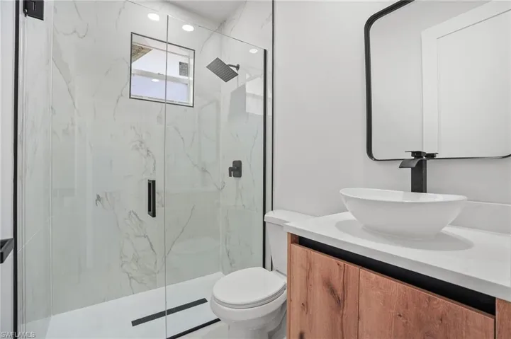 Bathroom featuring vanity and a marble finish shower