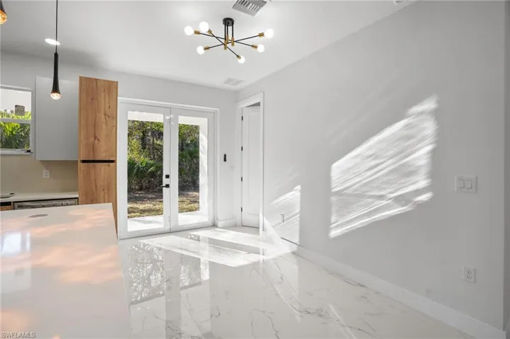 Unfurnished dining area with french doors, marble tiled flooring, and suspended lighting