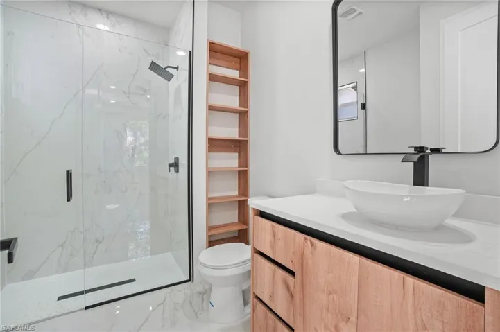 Bathroom with vanity, marble finish floors, and a marble finish shower