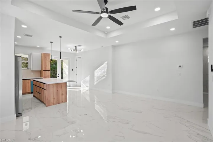 Kitchen featuring a raised ceiling, a kitchen island, modern cabinets, pendant lighting, and open floor plan