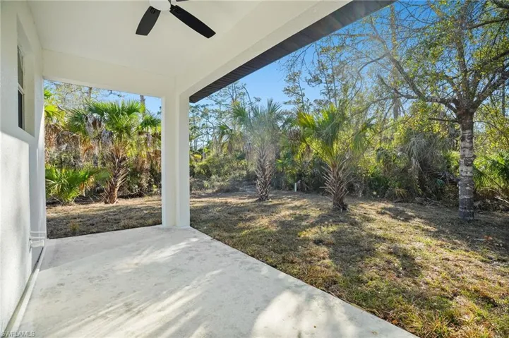 View of grassy yard featuring ceiling fan and a patio area