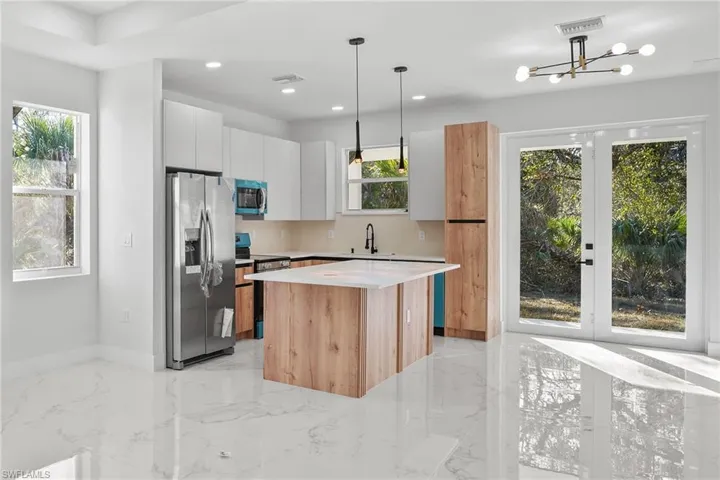 Two tone kitchen with stainless steel appliances, a kitchen island, modern cabinets, dual tone cabinets, and french doors