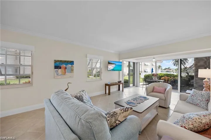 Living room with ornamental molding, plenty of natural light, and light tile patterned floors