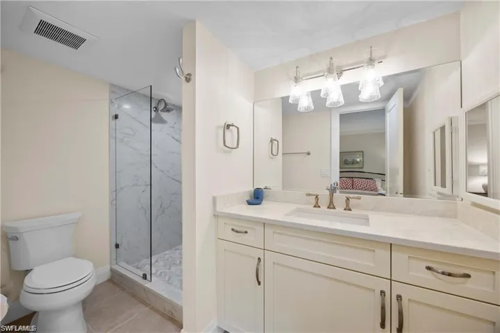 Ensuite bathroom featuring vanity, a marble finish shower, and light tile patterned flooring