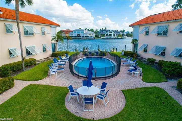 Community pool with a patio, a water view, and a lawn