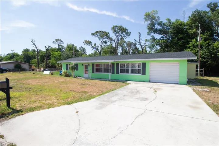 Ranch-style house with concrete driveway, an attached garage, and a front yard