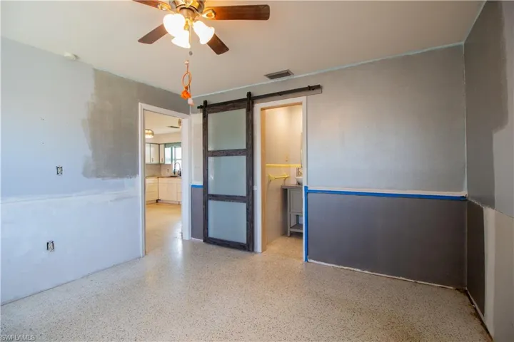 Spare room with speckled floor, visible vents, a barn door, and a ceiling fan