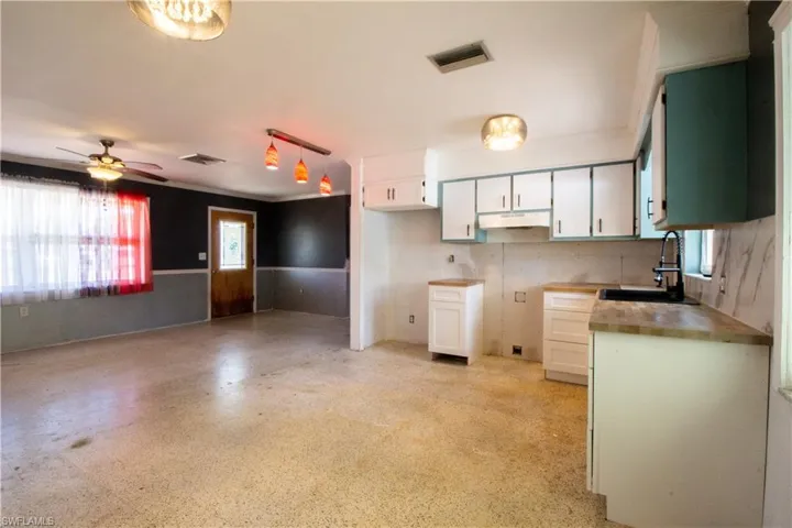Kitchen featuring under cabinet range hood, plenty of natural light, visible vents, and a sink