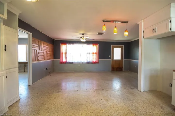 Spare room with wainscoting, ceiling fan, ornamental molding, and visible vents