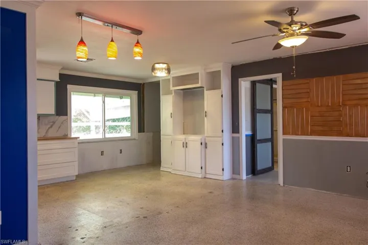 Empty room featuring crown molding, a ceiling fan, and light speckled floor